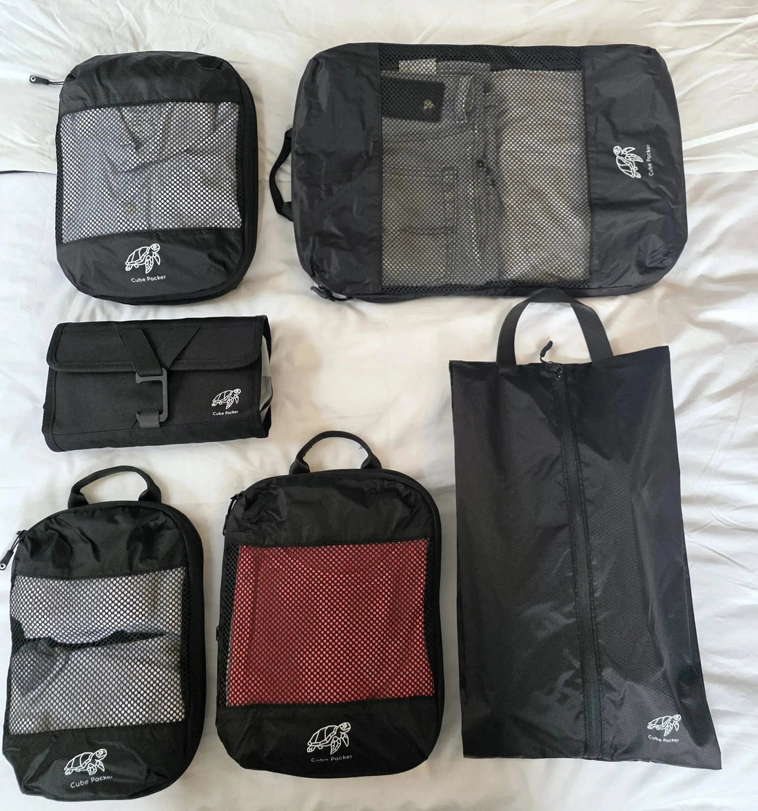 Cube Packer packing cubes, shoe bag, laundry bag and toiletries bag arranged on a bed