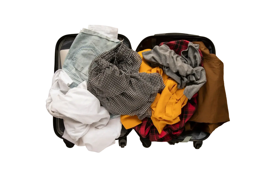Open suitcase with clothes loosely packed and disorganised, showing messy and stressful packing