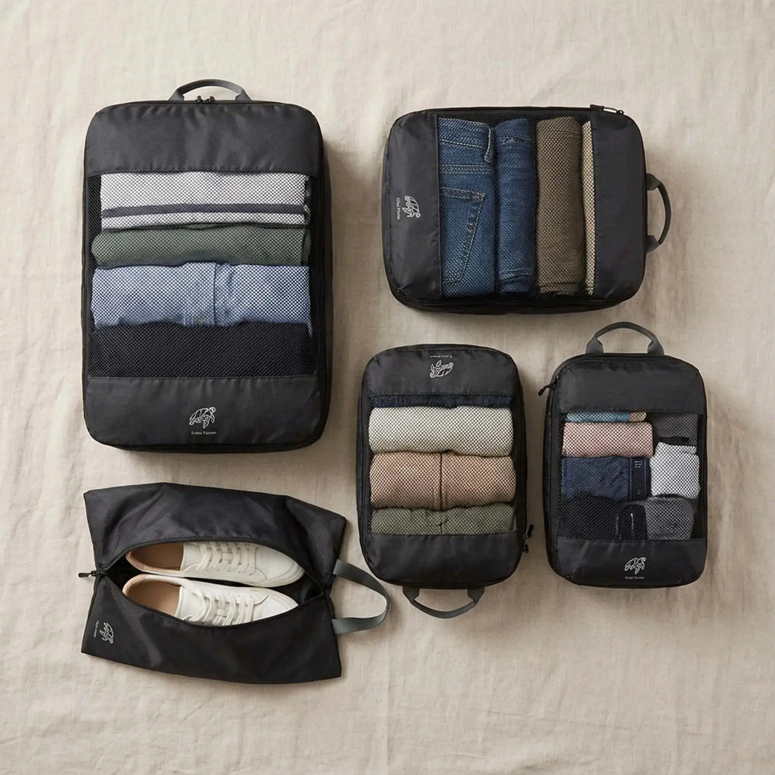 Different sized packing cubes laid out with clothing categories separated for travel organisation