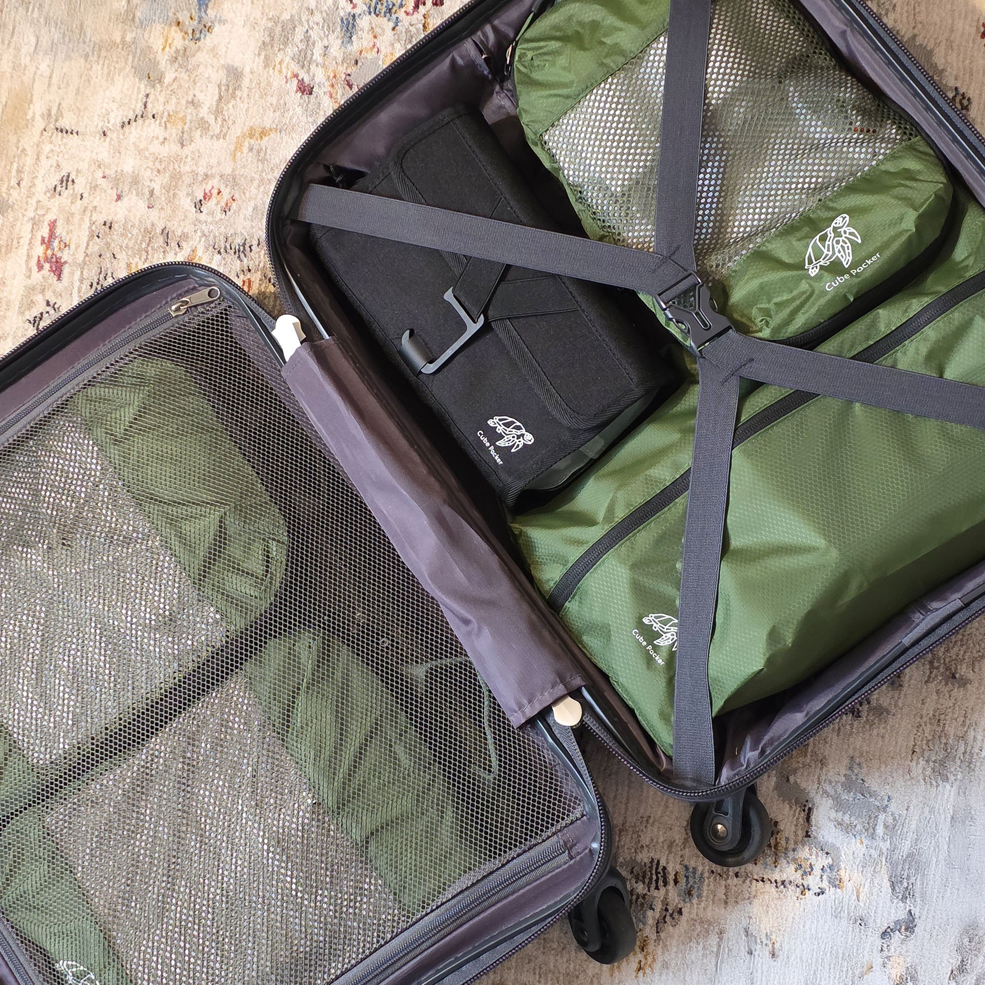 Open suitcase neatly packed with green Cube Packer compression cubes, black toiletries bag, and mesh compartments — showing efficient and organised travel packing system