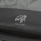 Close up of Cube Packer compression packing cube in black showing mesh fabric and logo detail