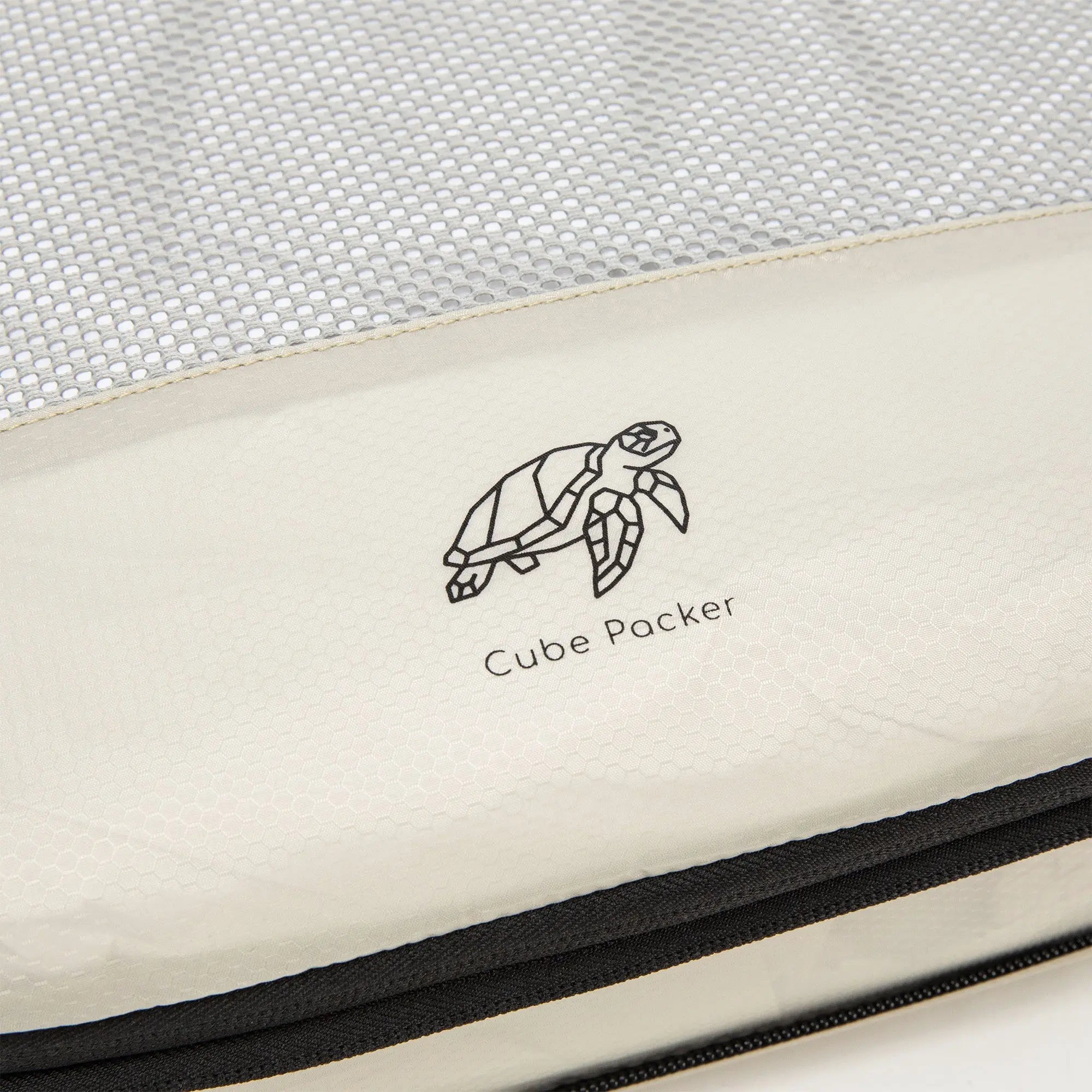 Close up of Cube Packer compression packing cube in cream showing mesh fabric and logo detail