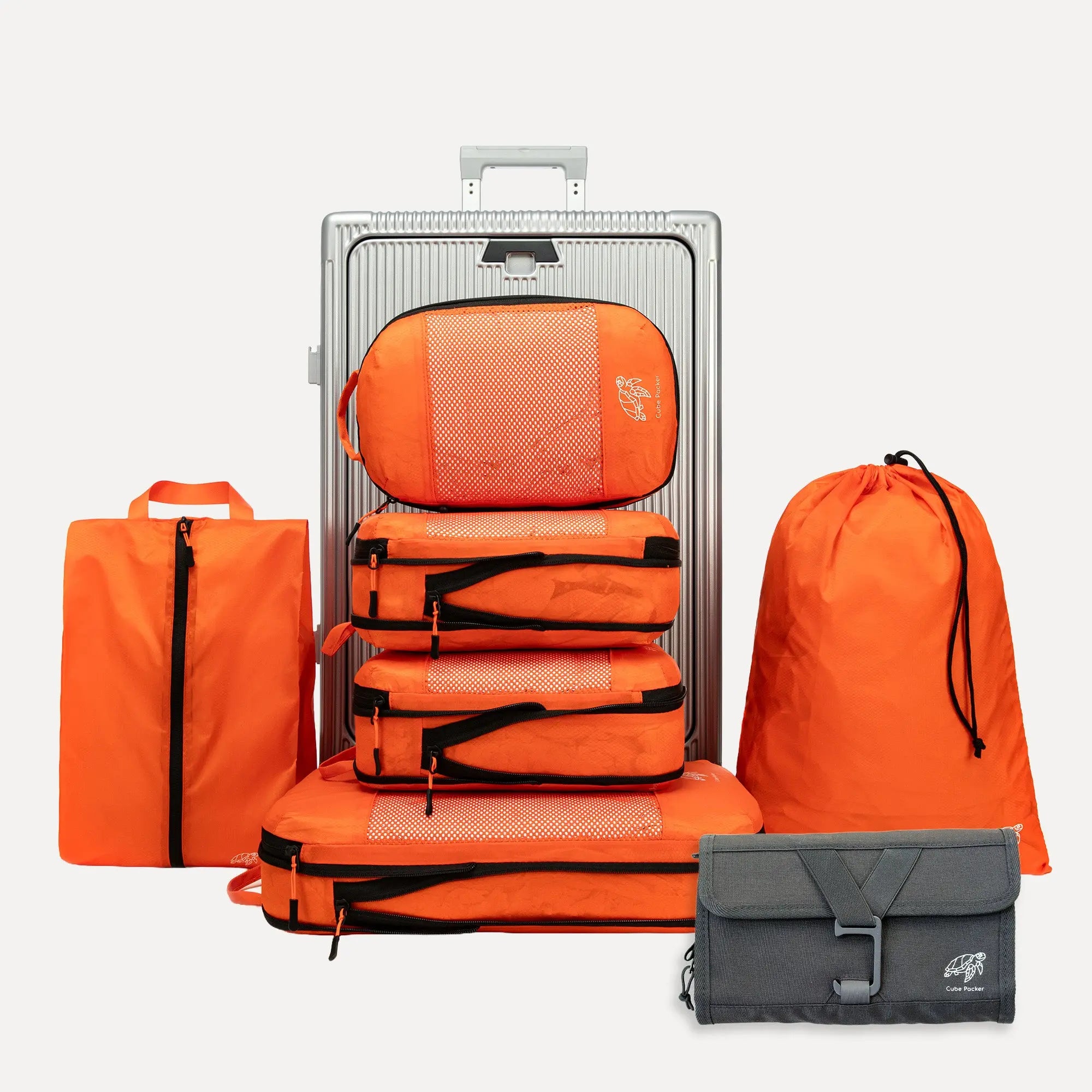 Cube Packer Travel System Bundle in Orange including packing cubes, shoe bag, laundry bag and toiletries bag arranged in front of a suitcase