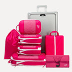 Cube Packer Travel System Bundle in Pink including compression packing cubes, shoe bag, laundry bag and toiletries bag arranged in front of a suitcase