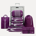 Cube Packer Travel System Bundle in Purple including compression packing cubes, shoe bag, laundry bag and toiletries bag arranged in front of a suitcase